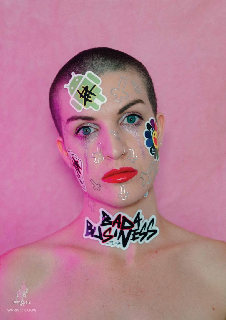 A lady with a shaved head with stickers on her body and face