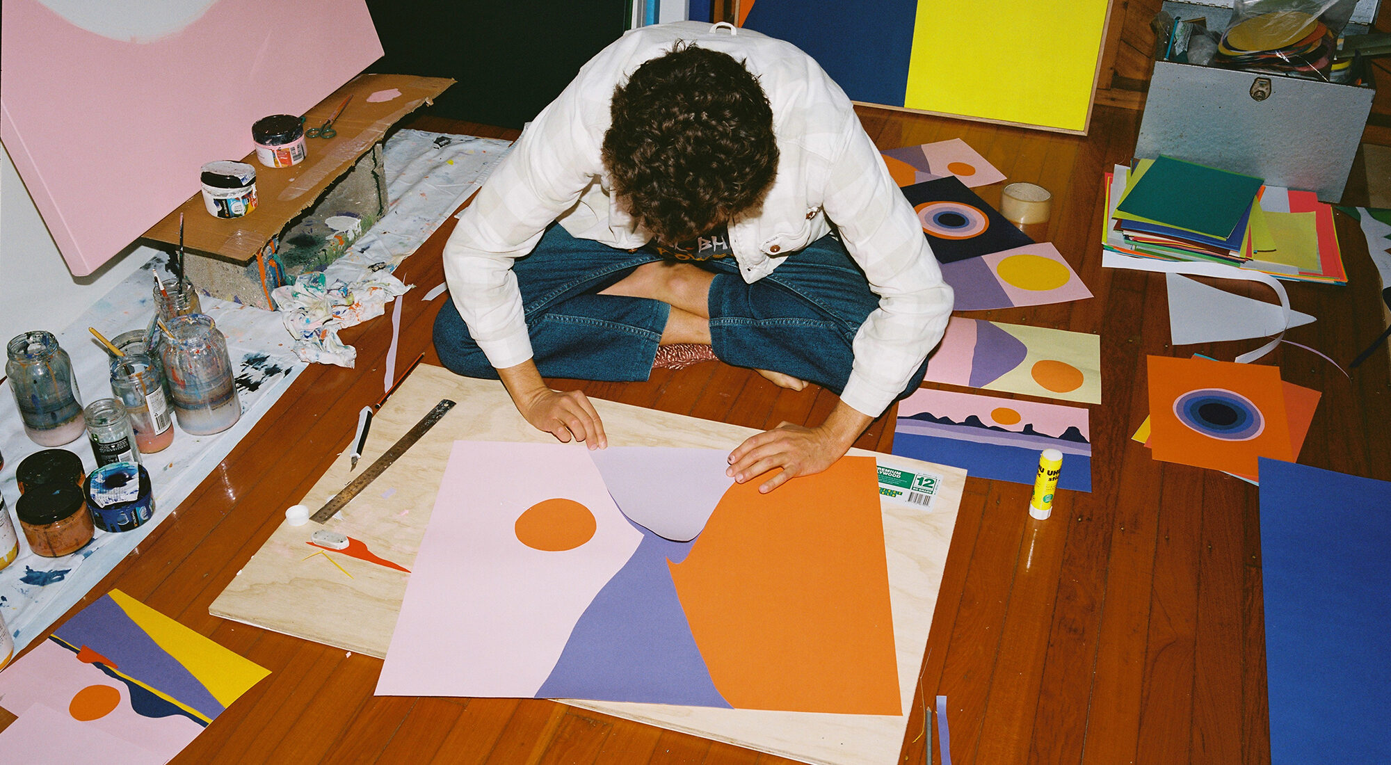 An artist working with paper on the ground.