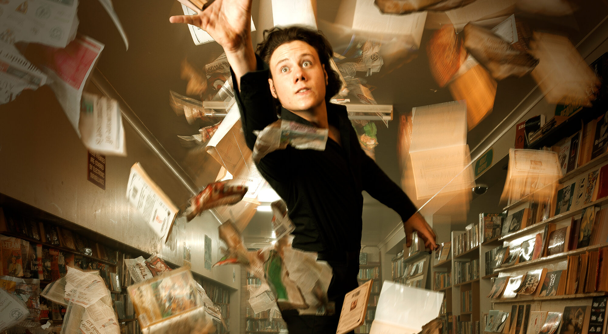 A person flying through a pile of paper in a bookstore.