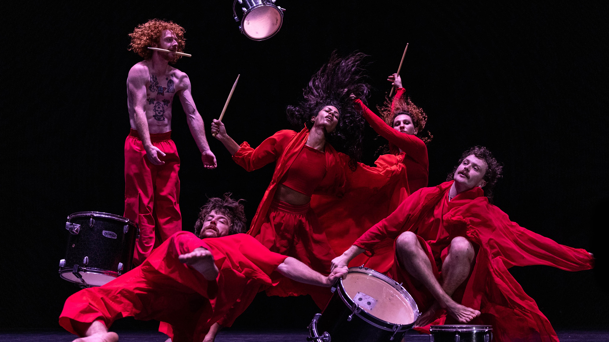 Dancers with drums, dressed in red.